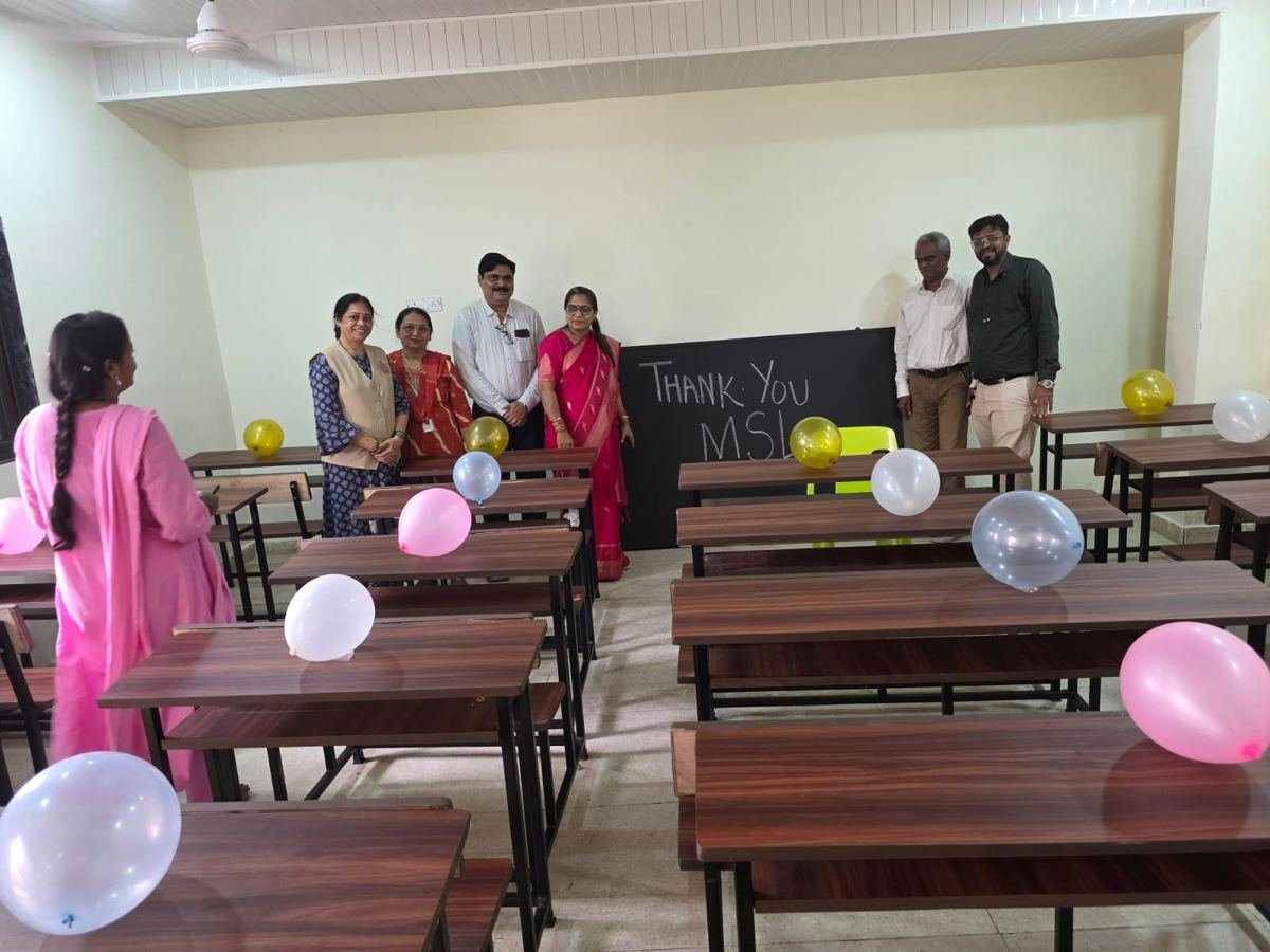 Guests and teachers in a classroom with the new benches